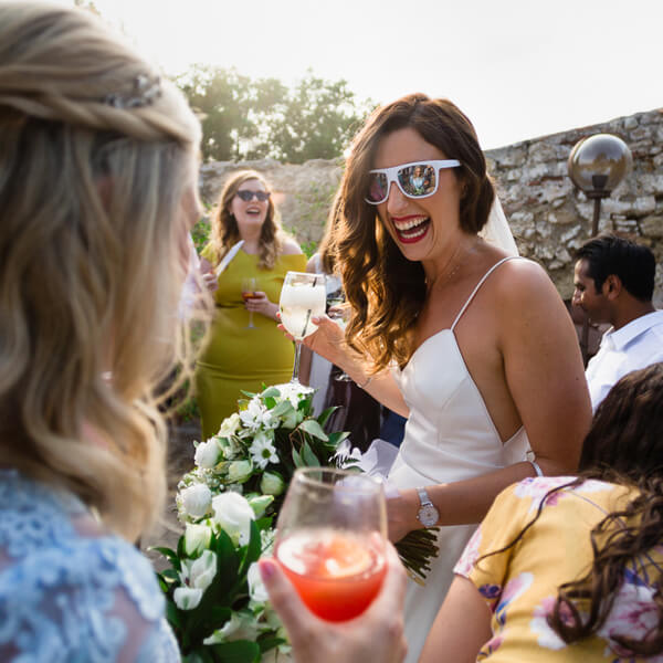 Bride with cocktail and wearing sunglasses laughing at Spanish Mountain Wedding